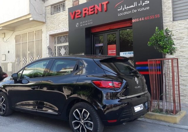 Renault Clio 4 noire devant l'agence V2 Rent Car
