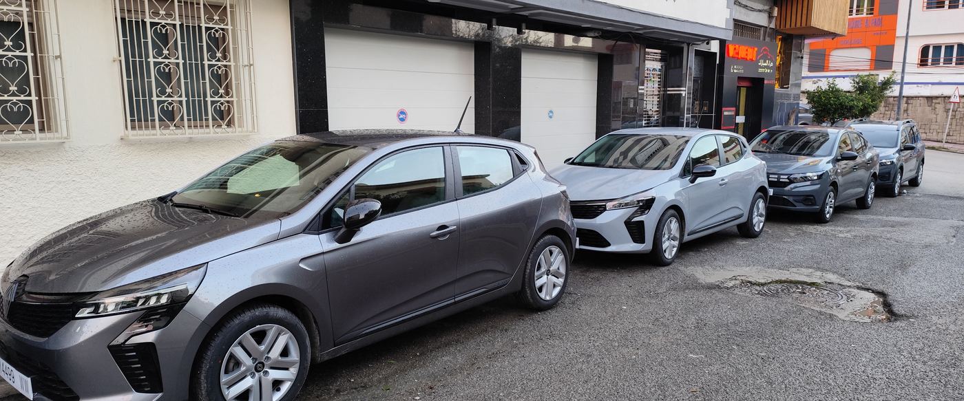 La flotte V2 Rent Car alignée devant l'agence : Clio, Corsa, Sandero